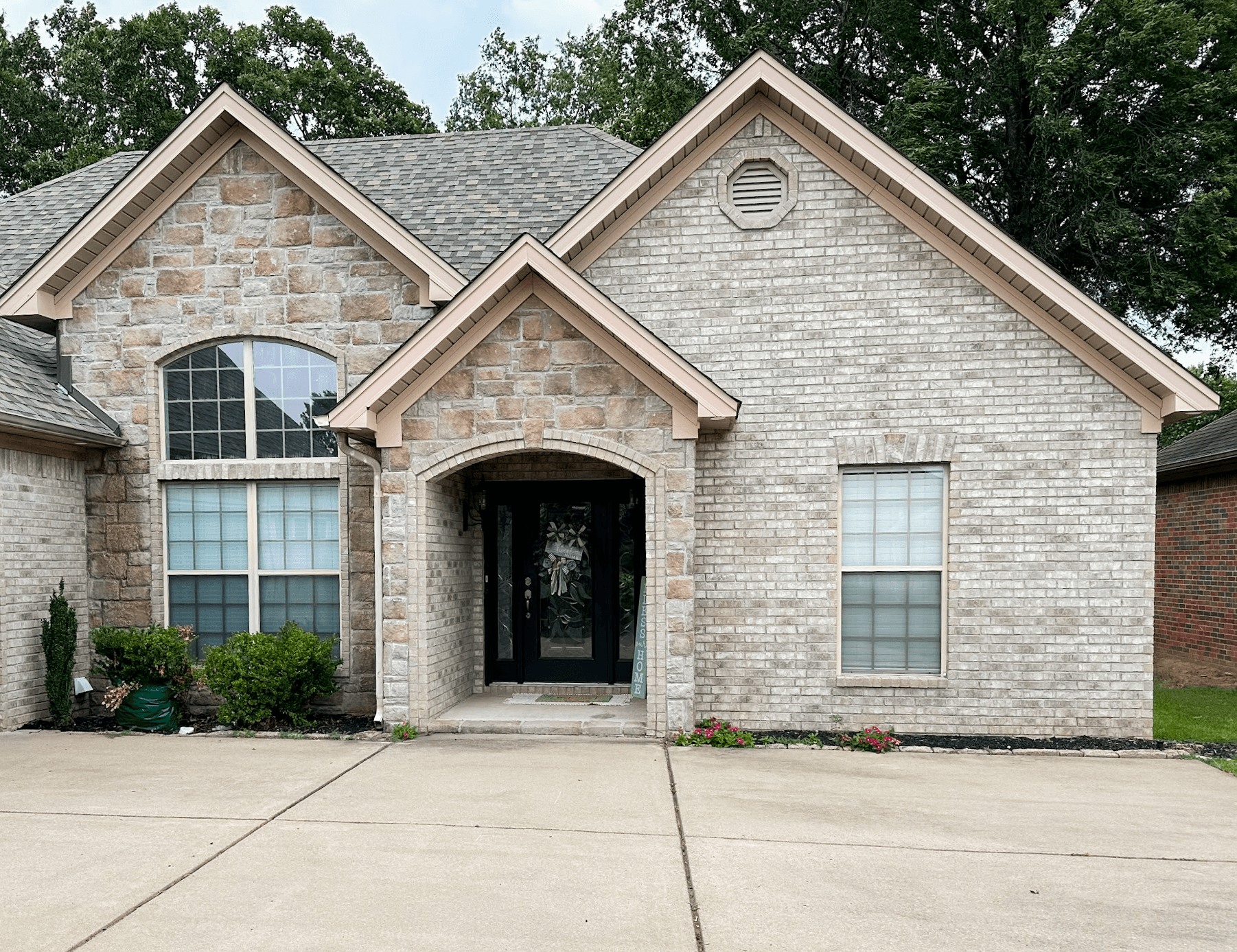 Completed WinChoice window installation on a stone and brick home with an arched entryway