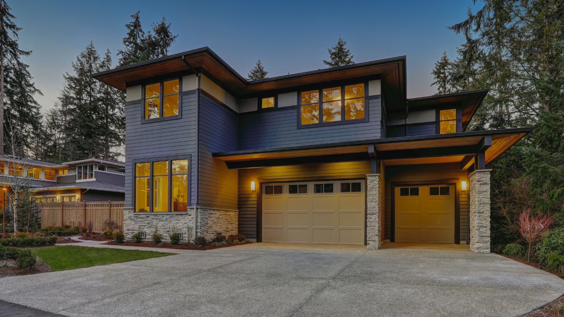 Large family home with garage, glowing with warm interior lights, and sleek professionally installed windows